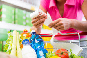 Start your food budget makeover. Woman with grocery receipt at cart